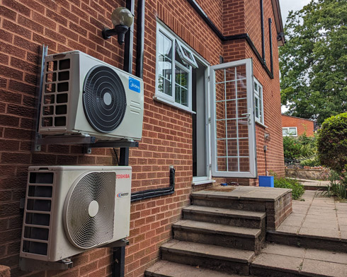 domestic twin split air conditioning units installed on outside wall of home